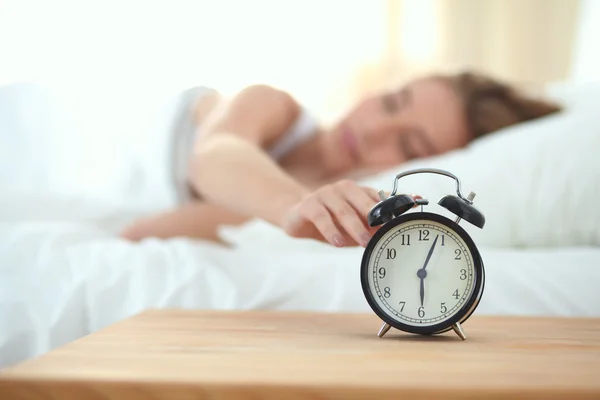 Evdeki yatak odasında uyuyan genç kadın ve çalar saat.