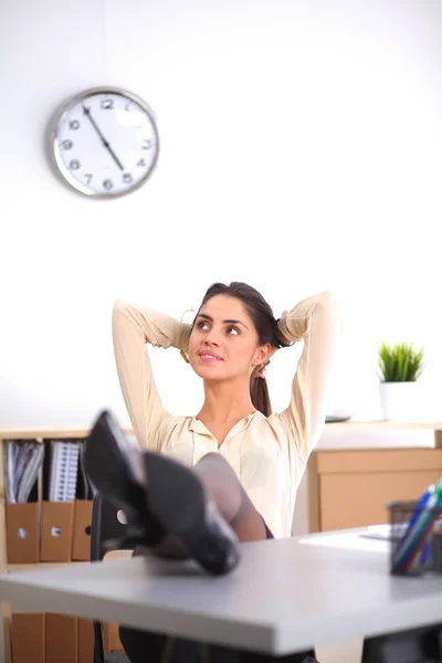 Geschäftsfrau entspannt sich mit den Händen hinter dem Kopf und sitzt auf einem Bürostuhl — Stockfoto