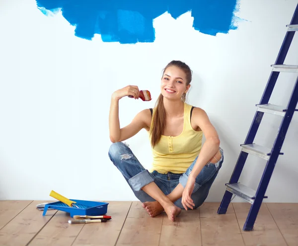 Portrait of female painter sitting on floor near wall after painting. — Stock Photo, Image