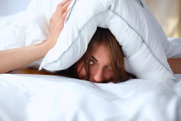 Mujer acostada en la cama y cerrando las orejas con almohada —  Fotos de Stock