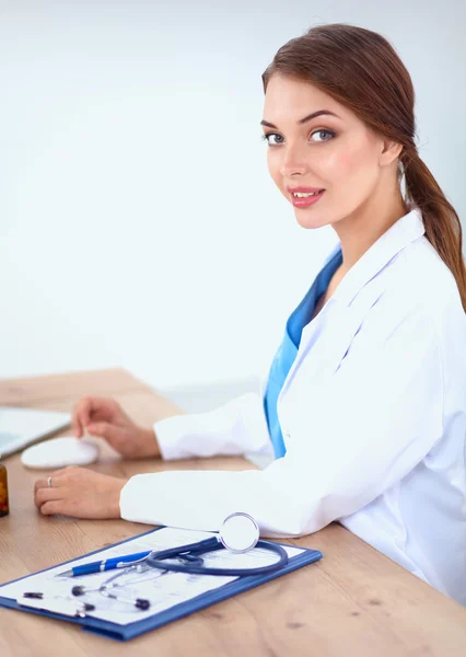 Belle jeune femme médecin souriante assise au bureau et écrivant. — Photo