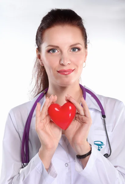 Jonge vrouw arts met een rood hart, staan op grijze achtergrond — Stockfoto
