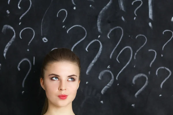 Young girl with question mark on a gray background — Stock Photo, Image