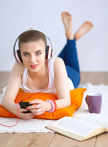 若い女性の上に横たわる床し、音楽に耳を傾ける — ストック写真