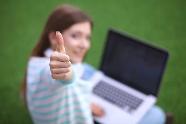 Young woman with laptop sitting on green grass — Stock Photo, Image