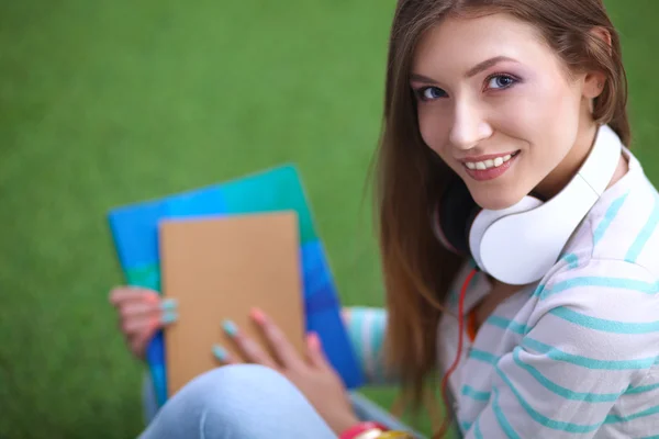 Jonge vrouw met laptop zittend op groen gras — Stockfoto