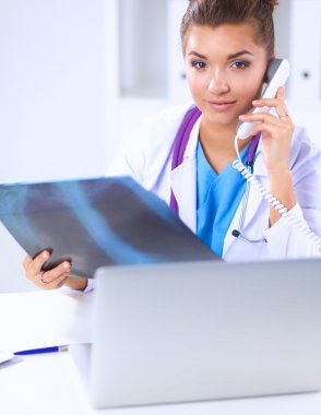 Masada oturan genç bayan doktor röntgen üzerinde çalışıyor.