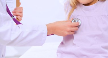 Kadın doktor ameliyatta steteskopla çocuğu muayene ediyor..