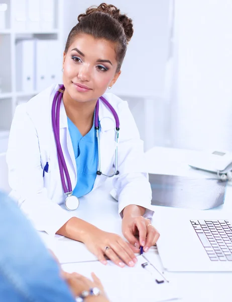 Læge og patient sidder på skrivebordet på kontoret - Stock-foto
