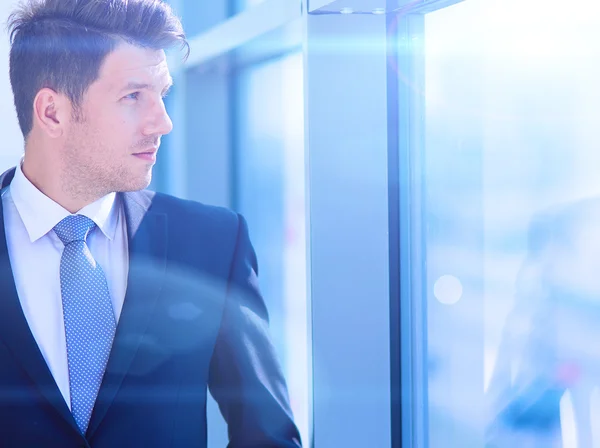 Porträt eines Geschäftsmannes, der am Fenster seines Büros steht — Stockfoto