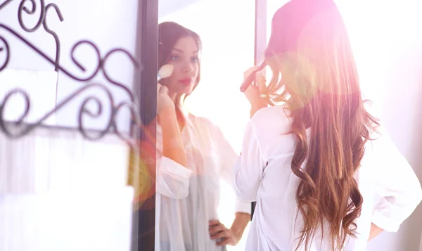 Молодая женщина смотрит на себя отражение в зеркале дома — стоковое фото