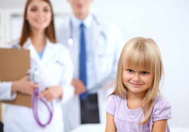 Kadın doktor ameliyatta steteskopla çocuğu muayene ediyor.