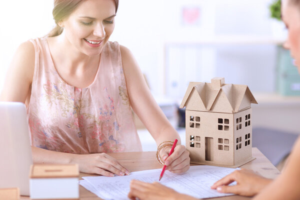 Portrait of female architect with blueprints at desk in office