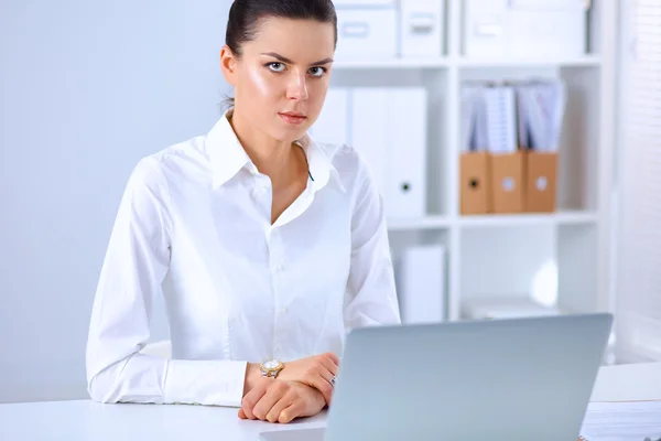 Atractiva mujer de negocios sentada en un escritorio con portátil en la oficina —  Fotos de Stock