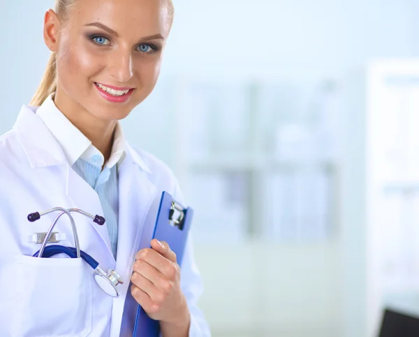 Médico sonriente con una carpeta en uniforme de pie en el hospital —  Fotos de Stock