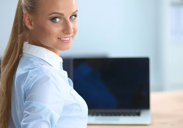 Attraente donna d'affari seduta su una scrivania con computer portatile in ufficio — Foto Stock