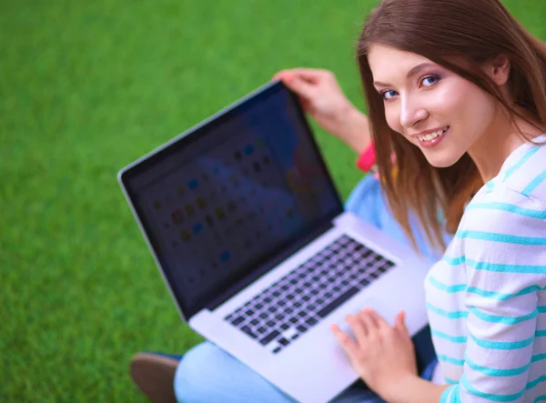 Jeune femme avec ordinateur portable assis sur l'herbe verte — Photo