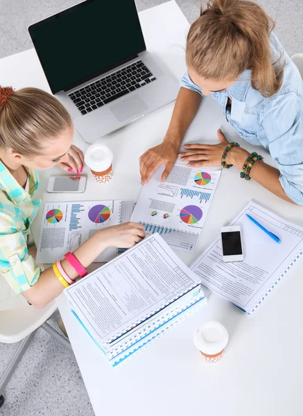 Två kvinnor arbetar tillsammans på kontoret, sitter på skrivbordet — Stockfoto