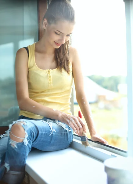 Vrouw schilderij muur van een appartement met een penseel zorgvuldig afwerking af rond raamkozijn — Stockfoto