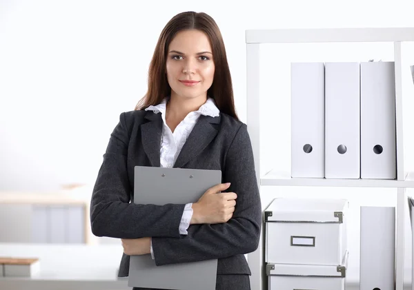 Attrayant jeune femme d'affaires debout près du bureau avec dossier dans le bureau — Photo