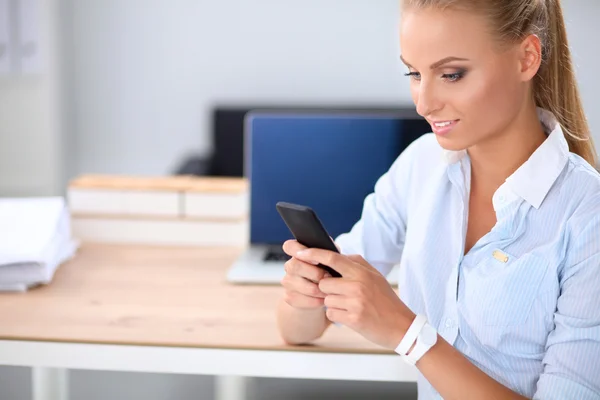 Businesswoman sending message with smartphone sitting in the office — Stock Photo, Image