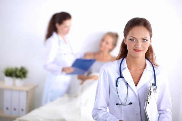 Médico sonriente con una carpeta en uniforme de pie en el hospital —  Fotos de Stock