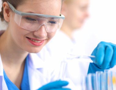 Kadın araştırmacı, beyaz arka planda izole edilmiş ilaç şişeleri ve mataralarla çevrili.