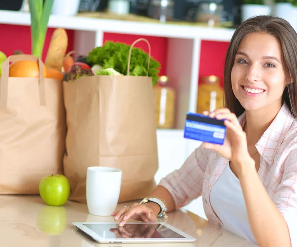 Smiling woman online shopping using tablet and credit card in kitchen — Stock Photo, Image