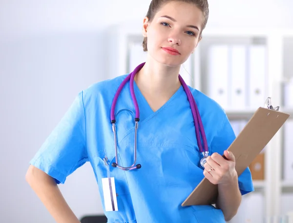 Lächelnde Ärztin mit Ordner in Uniform steht im Krankenhaus — Stockfoto