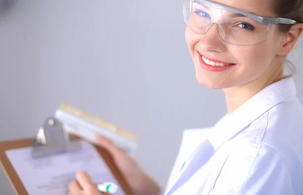 Médica sorridente com uma pasta em uniforme de pé no hospital — Fotografia de Stock