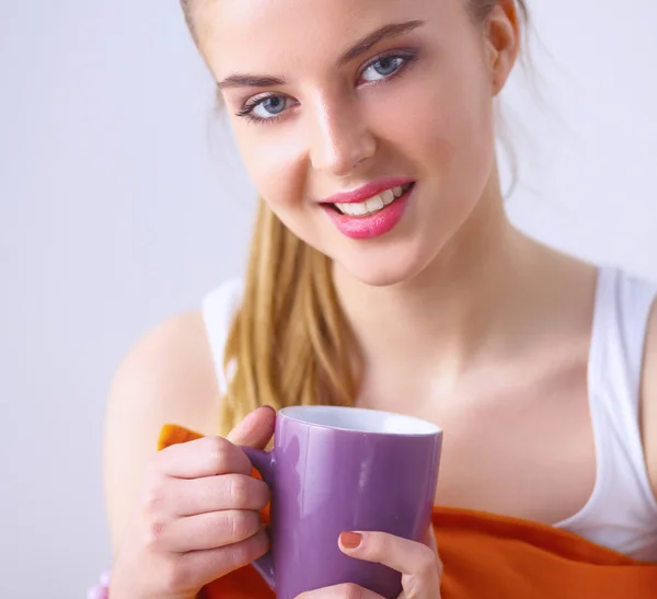 Jeune femme assise avec un oreiller et tenant une tasse de thé — Photo