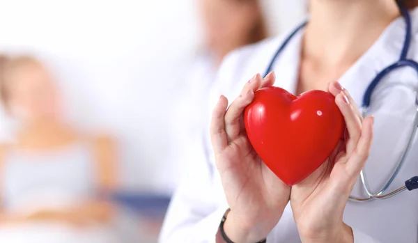 Mujer joven doctora sosteniendo un corazón rojo, aislado sobre fondo blanco —  Fotos de Stock