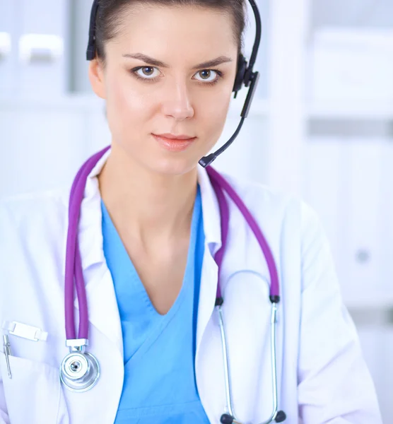 Doctor wearing headset sitting behind a desk with laptop over grey background — Stock Photo, Image
