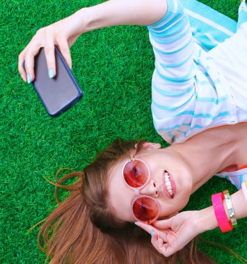 güzel ve genç birbayan yeşil çim yalan onu telefonla selfie yapma