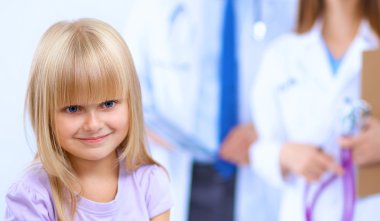 Kadın doktor ameliyatta steteskopla çocuğu muayene ediyor.