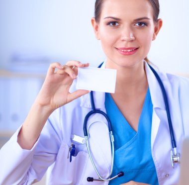 Güzel, genç, gülümseyen bayan doktor masada oturuyor ve yazıyor..