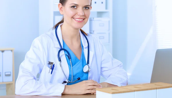 Belle jeune femme médecin souriante assise au bureau et écrivant. — Photo