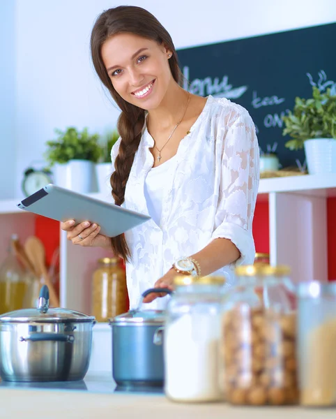 Mujer joven usando una tableta para cocinar en su cocina —  Fotos de Stock