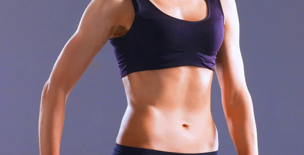 Muscular young woman  standing on gray background — Stock Photo, Image