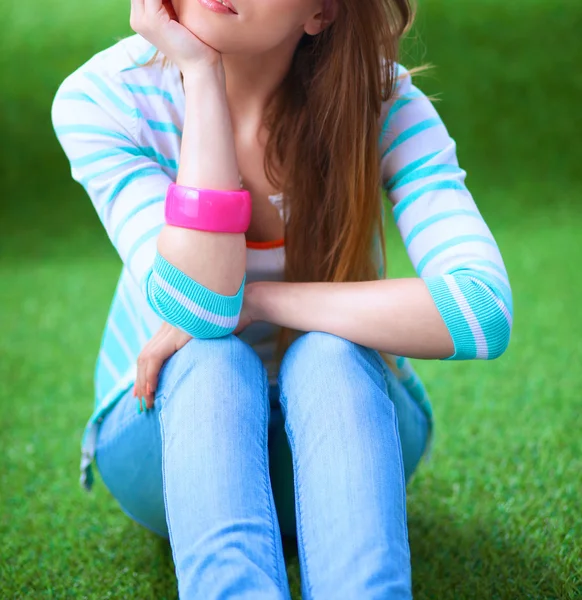 Belle jeune femme assise sur l'herbe verte — Photo