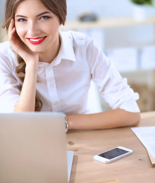 Aantrekkelijke zakenvrouw zit op het bureau in het kantoor — Stockfoto