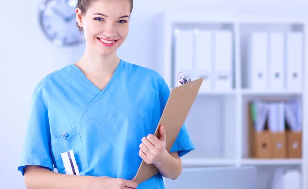 Médico sonriente con una carpeta en uniforme de pie en el hospital —  Fotos de Stock