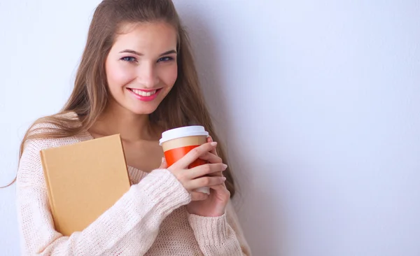 Portrait d'une jeune femme avec une tasse de thé ou de café, tenant un livre — Photo