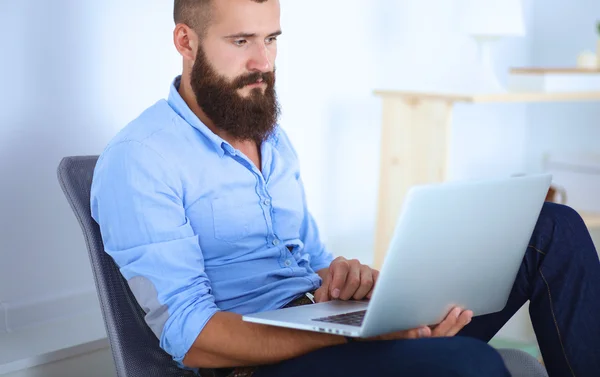 Przystojny młody człowiek siedzi i pracuje na laptopie — Zdjęcie stockowe