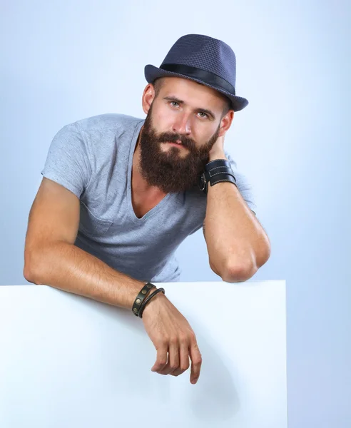 Portrait of young man in hat standing near blank, isolated on white background — Stock Photo, Image