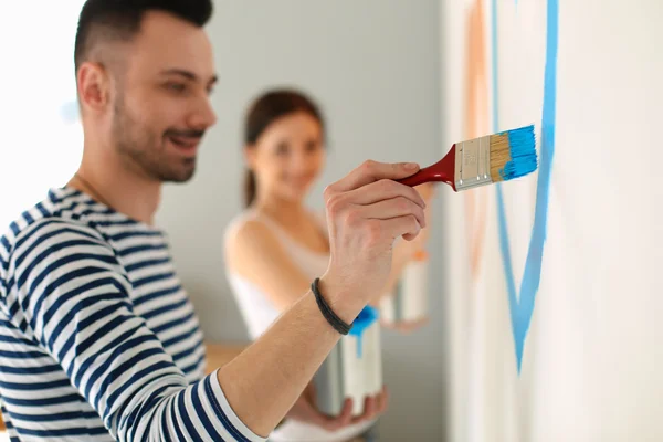 Porträt eines glücklich lächelnden jungen Paares beim Bemalen der Innenwand des neuen Hauses — Stockfoto