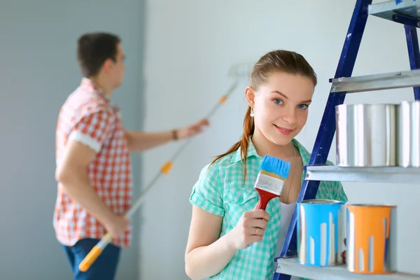 Retrato de feliz sorrindo jovem casal pintura parede interior da nova casa — Fotografia de Stock