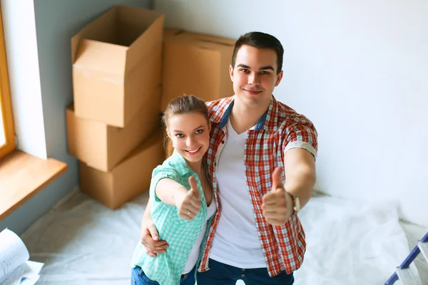 Jovem casal feliz em sua nova casa de design moderno mostrando polegares para cima — Fotografia de Stock