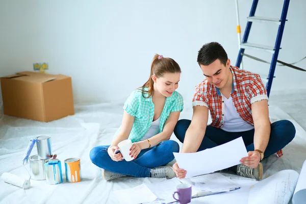 Ungt par sitter på golvet med lägenhet plan — Stockfoto