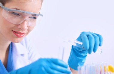 Kadın araştırmacı, beyaz arka planda izole edilmiş ilaç şişeleri ve mataralarla çevrili.